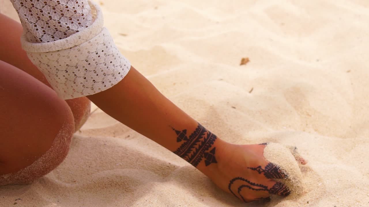 헤나 문신을 한 아름다운 여성이 손에 있는 모래를 슬로우 모션으로 집어든다