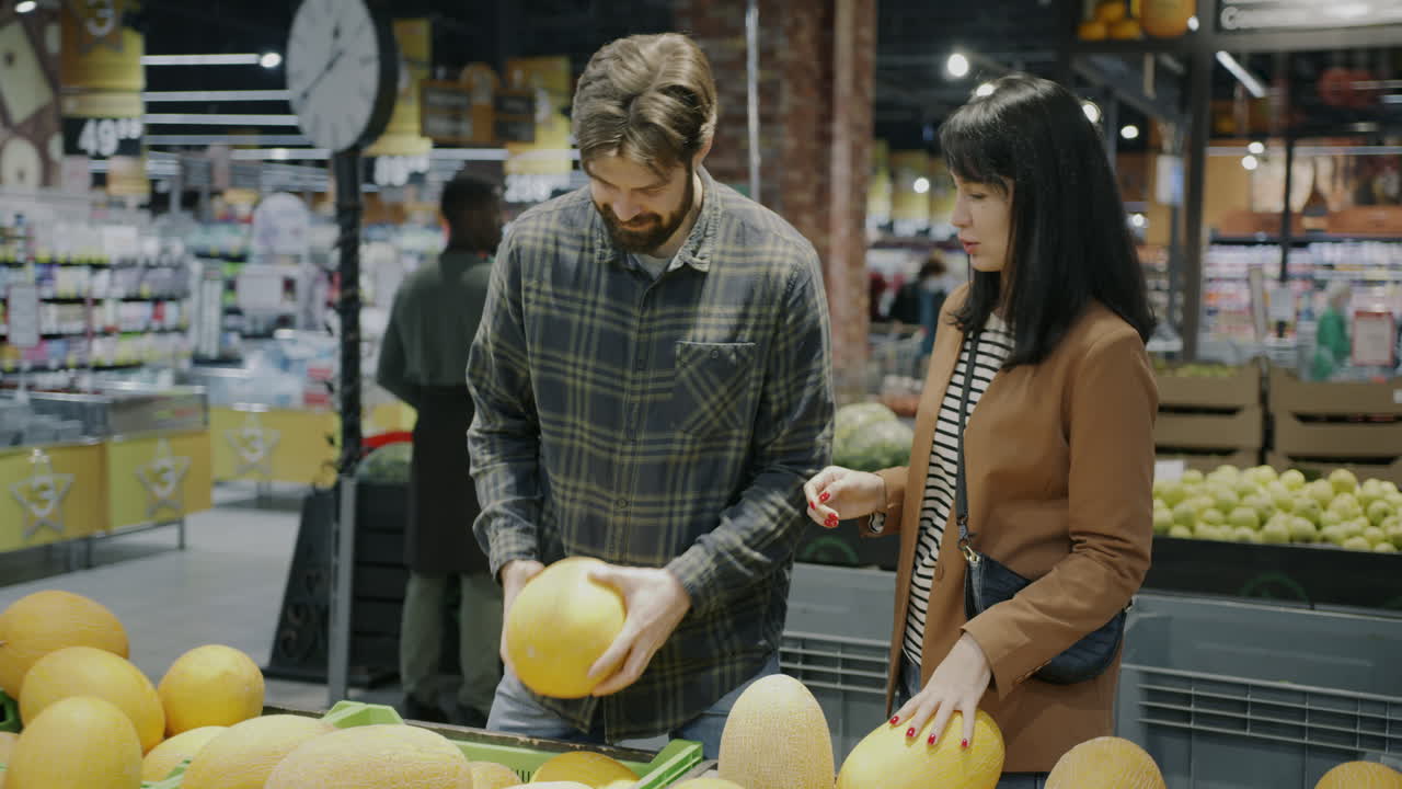 Couple Shopping for Cantaloupe in a Grocery Store