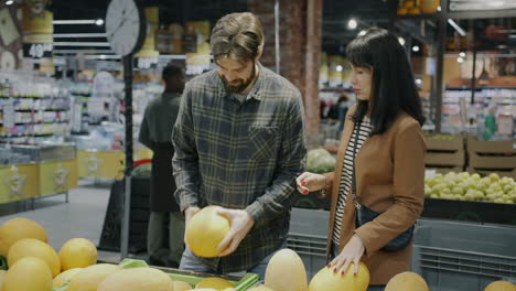 couple shopping for cantaloupe in a grocery store