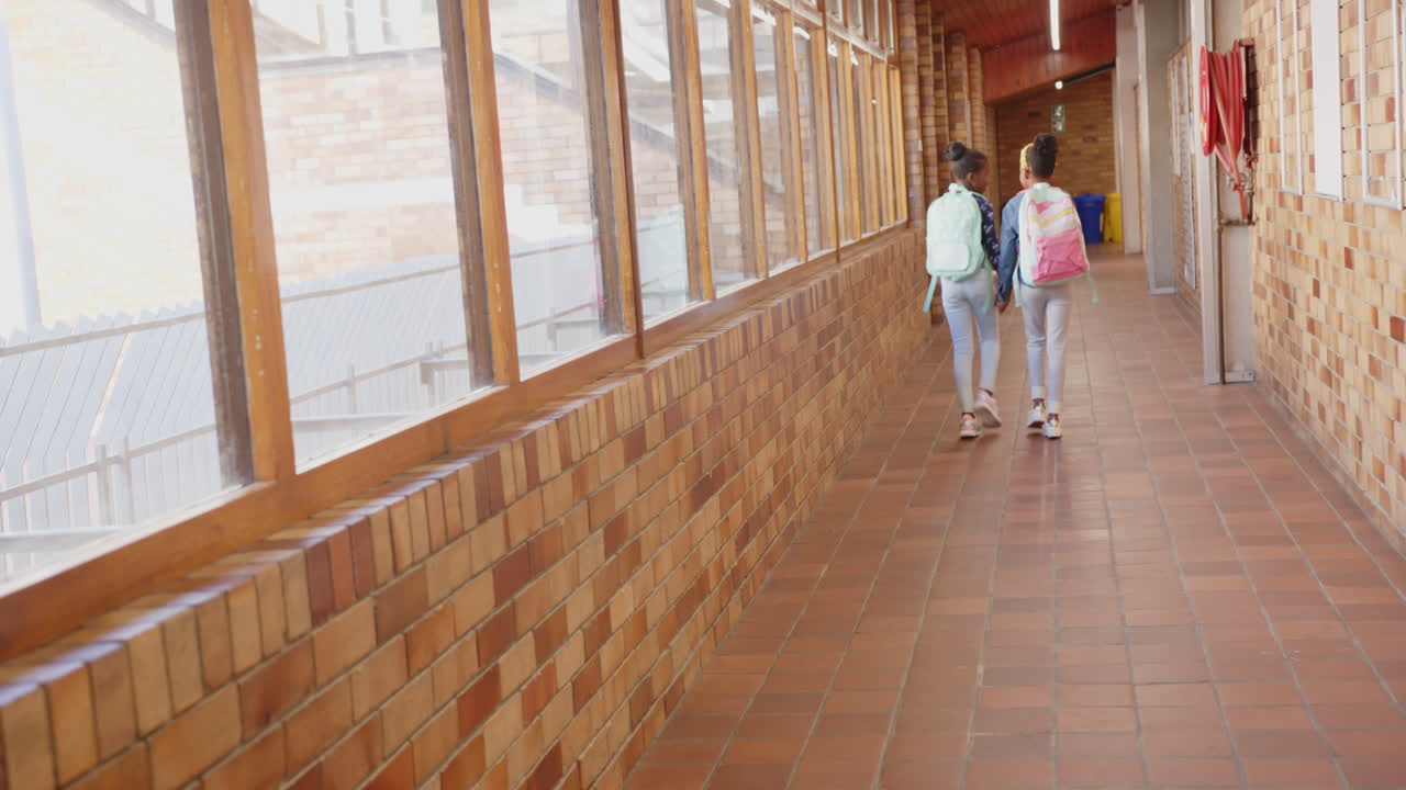 Walking in school hallway, two girls with backpacks heading to class
