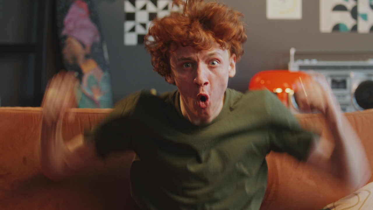 Young Man Watching Sports on TV and Cheering with Excitement