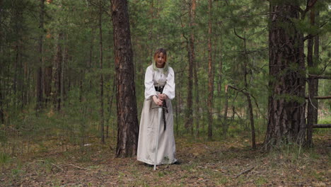 teenage girl in medieval dress sticks sword into ground