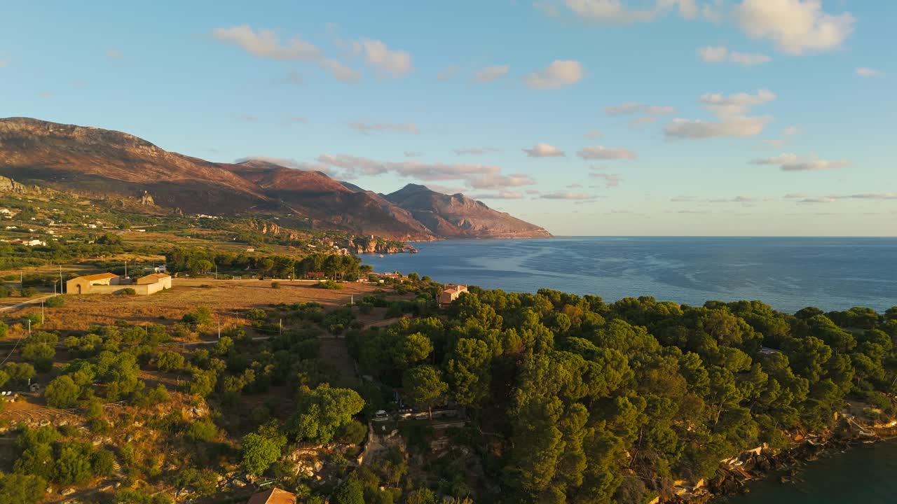 Static shot of Guidaloca Beach and Sicilian coast in Sicily, Italy during golden sunrise, showing tranquil ocean, cliffs, and natural scenery