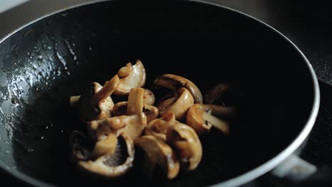 chef flips mushrooms in a frying pan. professional cooking.