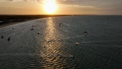 aerial: kiteboarders on the atlantic ocean at sunset with golden hour colors in cajueiro da praia, piaui, brazil, pan drone shot