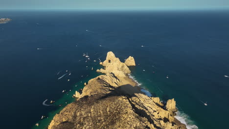 Aerial-view-backwards-over-the-Cabo-San-Lucas-rock-formation,-in-sunny-Mexico