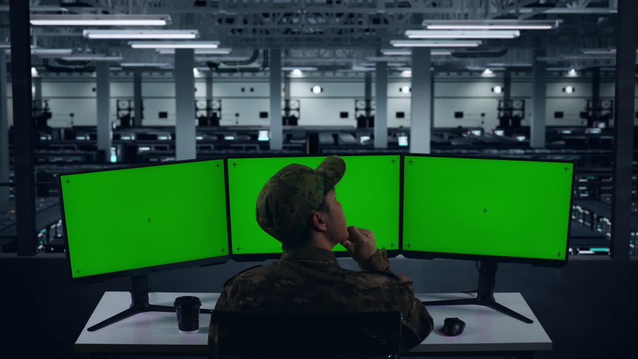 vista de atrás de los militares asiáticos pensando en algo luego levantando su dedo índice mientras trabajaba con simulacro de múltiples monitores de computadora en el centro de datos