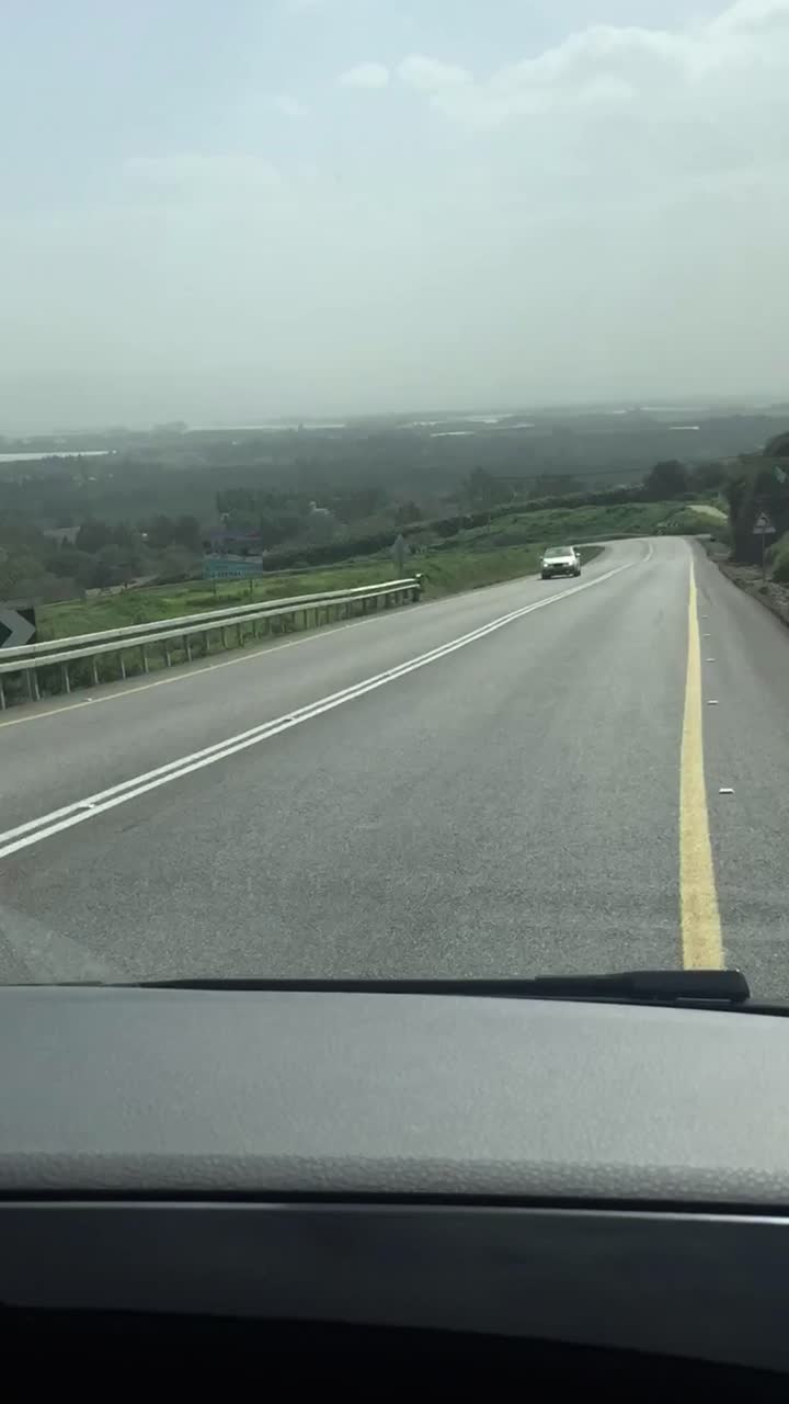 POV alla guida su una strada tortuosa con vista su un lago panoramico