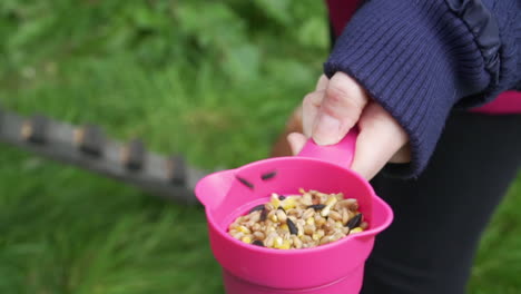 Zeitlupe-Klappert-Mit-Einer-Tasse-Hühnerfutter,-Um-Ihre-Aufmerksamkeit-Zu-Erregen