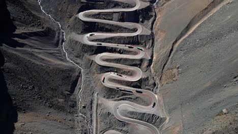 tilt up aerial view of the cuesta caracoles road, cargo trucks going down the curves, border between chile and argentina