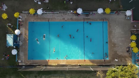 people and tourist having fun inside swimming pool during summer - aerial top down