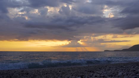 Zeitraffer-Dunkler-Wolken,-Die-Sich-Bei-Schönem-Sonnenuntergang-Mit-Gelbem-Himmel-über-Meer-Und-Strand-Bewegen