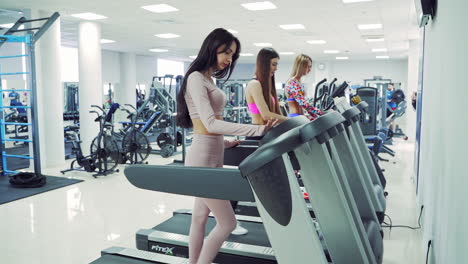 athletic young sporty women running on treadmill in gym. pretty girls in sportswear training in a sport center using treadmills. healthy lifestyle.