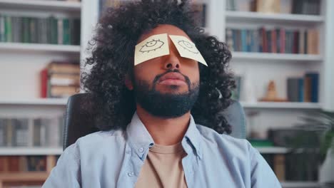 tired young arabian man sleeps working with paper stickers in front of eyes