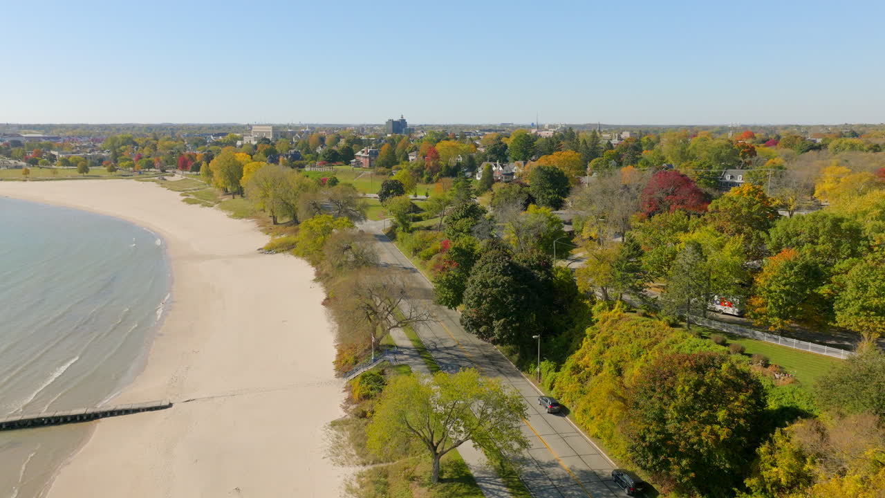 Drone aerial over a road along Lake Michigan in Sheboygan, Wisconsin with houses, trees, and a pleasant neighborhood view on a colorful autumn day