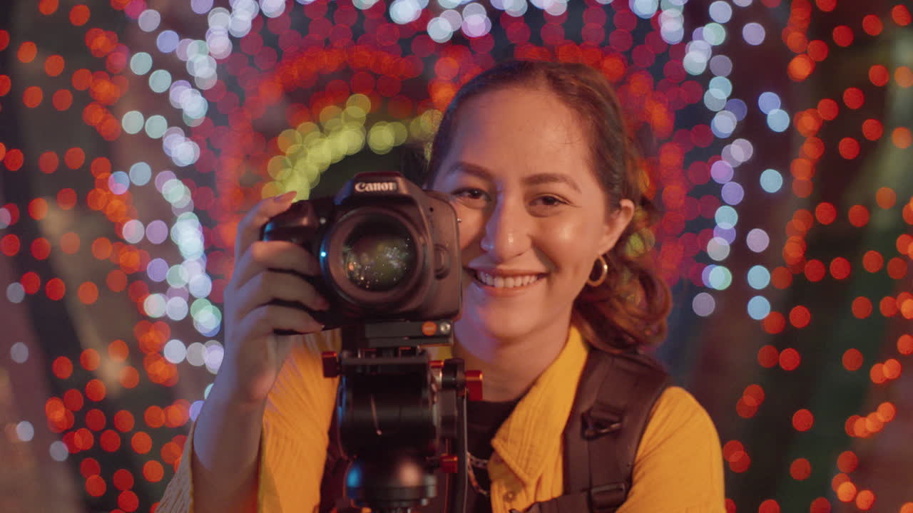 다채로운  ⁇ 박이는 조명 보케 배경에 dslr 카메라로 사진을 찍는 여성 사진작가