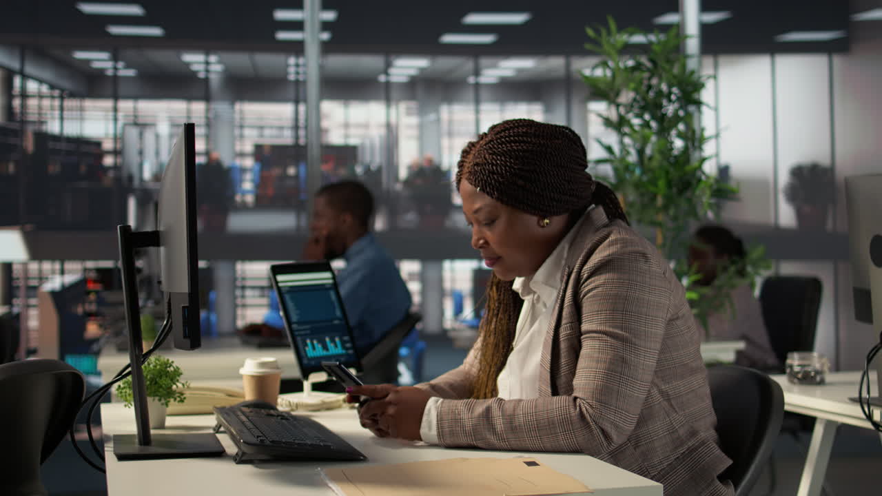 mujer de negocios trabajando en computadora y teléfono inteligente en una oficina moderna