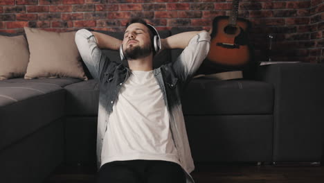 young musician man listening to music with wireless headphones and singing at home