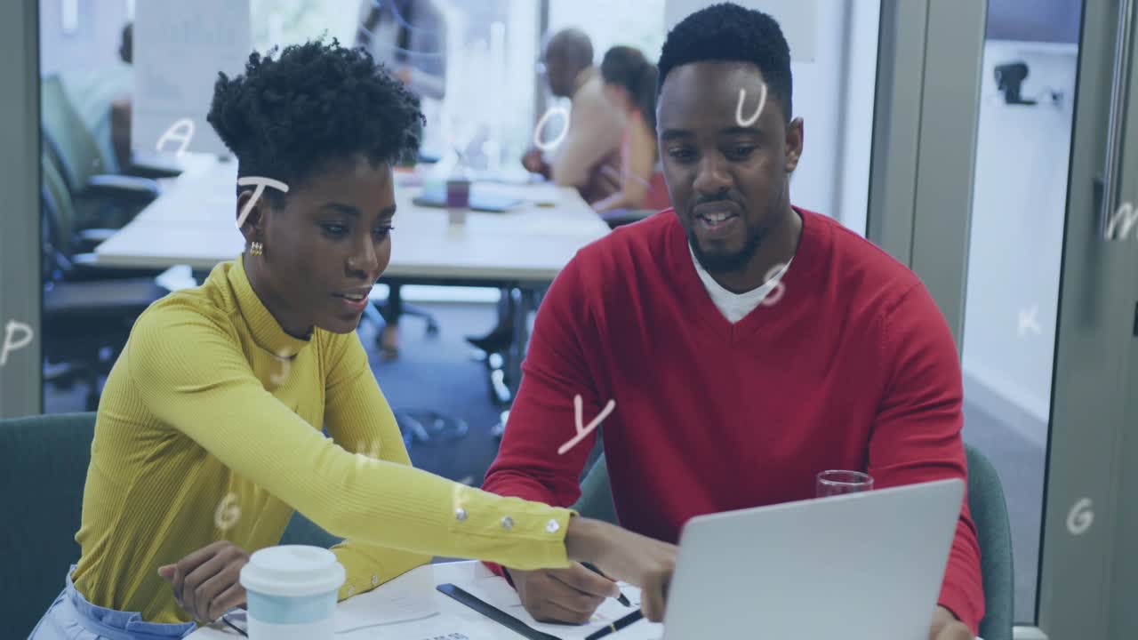 Woman leaning then pointing at laptop, man taking notes, floating letters guiding business review