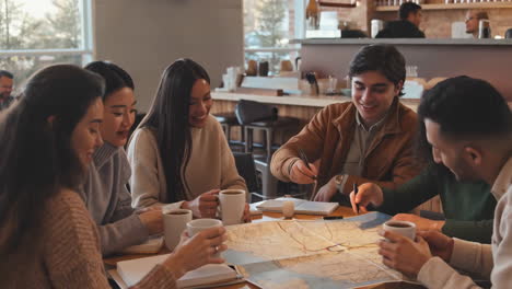 group of students studying a map in a coffee shop