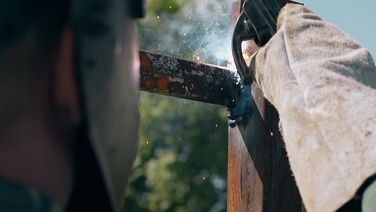 느린 움직임 가까운 보기 작업자  ⁇ 빛이 비치는 날 금속 울타리를 용접