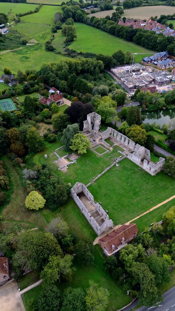 Portrait aerial drone pans right over Bishop’s Waltham in town, capturing historic buildings, streets, and autumn trees bathed in warm golden sunset light, creating a scenic and peaceful village view