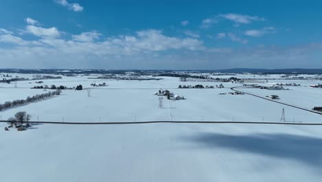 aerial lateral wide shot of snowy winter landscape in rural area at sunny day