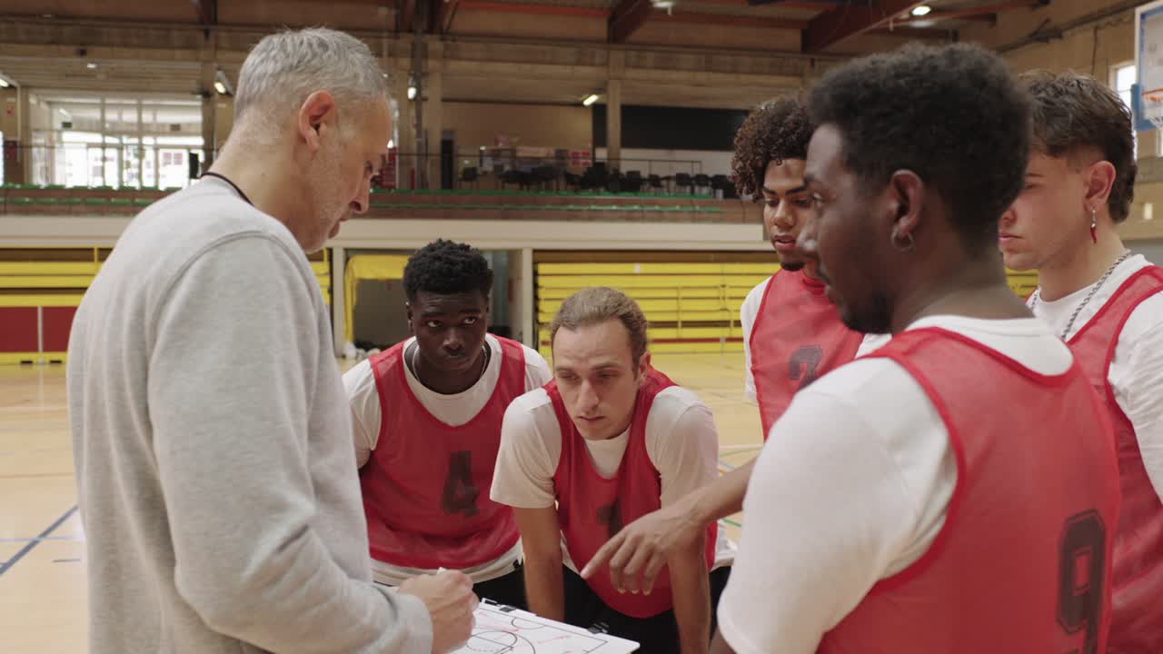 Basketballteam hört dem Trainer auf dem Spielfeld zu
