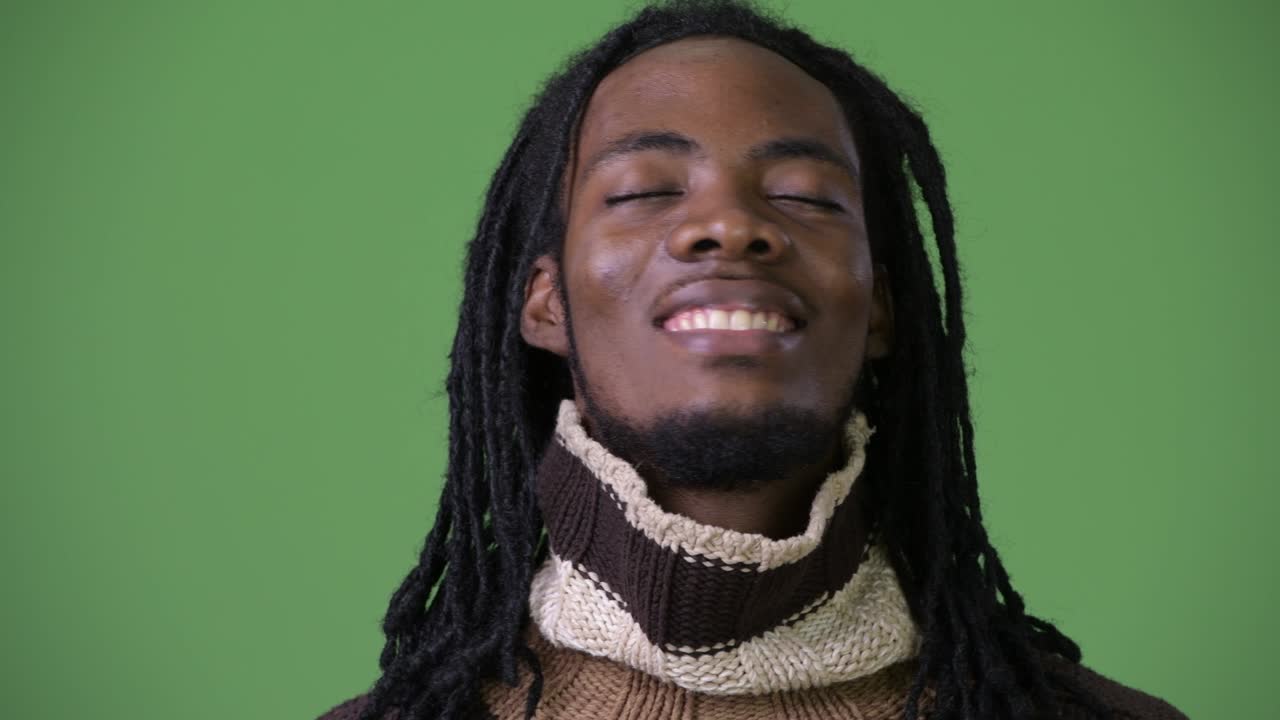 joven hombre africano guapo con dreadlocks contra un fondo verde