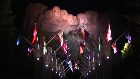 uma visão noturna do monte rushmore em luzes com a avenida das bandeiras em primeiro plano