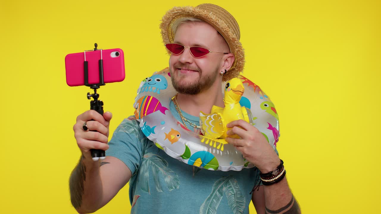 hombre blogger viajero con gafas de sol, tomando selfies en el teléfono móvil, comunicándose por video llamada en línea