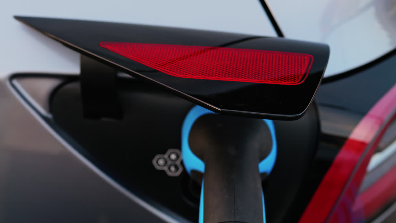 Close up of a blue electric car charger plugged into a car