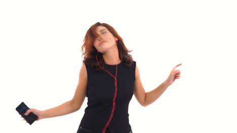 joyful young girl in black dress listening to the music with her earphones and having fun dancing isolated on the white background