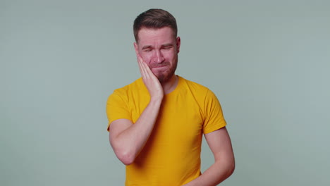 man touching cheek suffering from toothache cavities or gingivitis waiting for dentist appointment