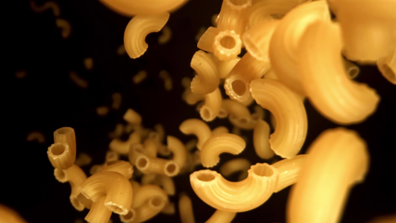 Pasta Maccheroni Cruda che Cade al Rallentatore su Sfondo Nero.