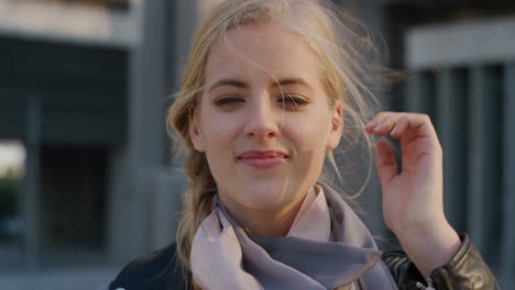 portrait happy young blonde woman smiling running hand through hair enjoying relaxed windy day in city at sunset independent caucasian female