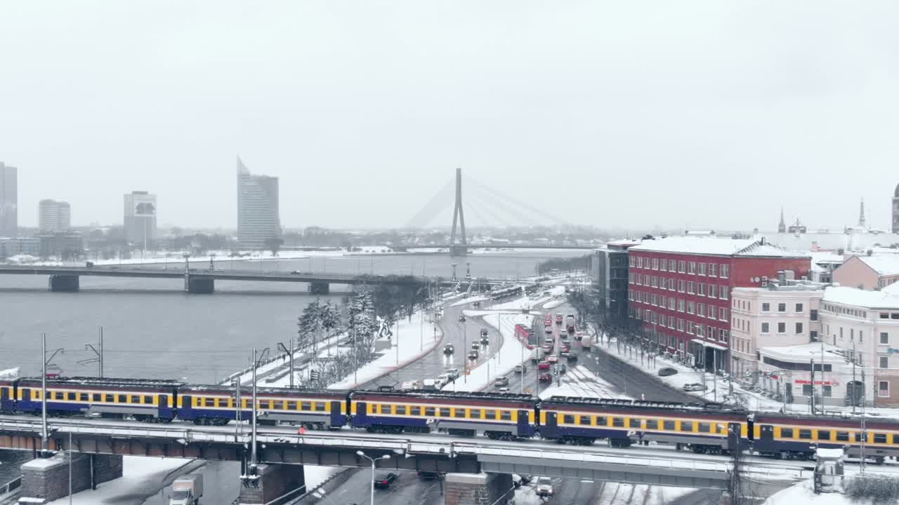 примечательный желтый поезд едет по городу, покрытому снегом, с воздуха, панорамирование слева