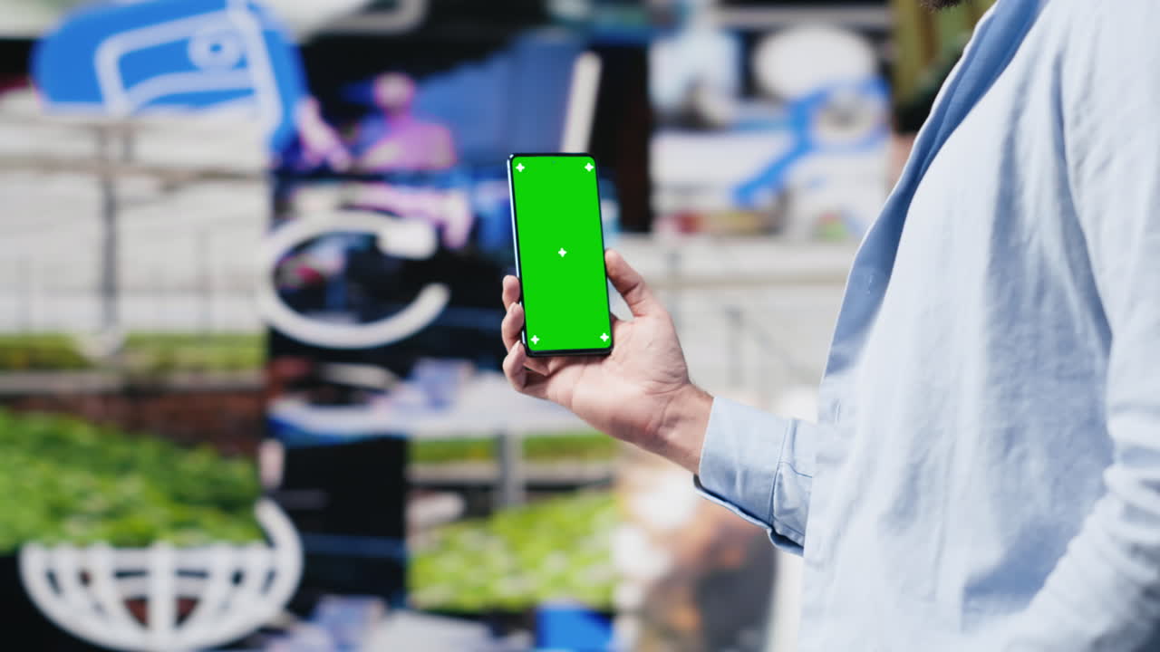 Young adult holds phone with chroma key screen and connecting on socials