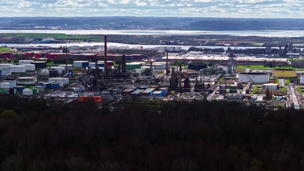 A sprawling industrial refinery with numerous tanks and chimneys situated by the Seine River. Ideal for environmental or industrial-themed projects.