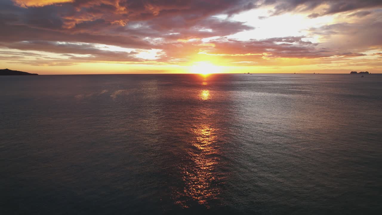 Droneflyvning over naturskøn strand med farverig solnedgang i horisonten, 4K.