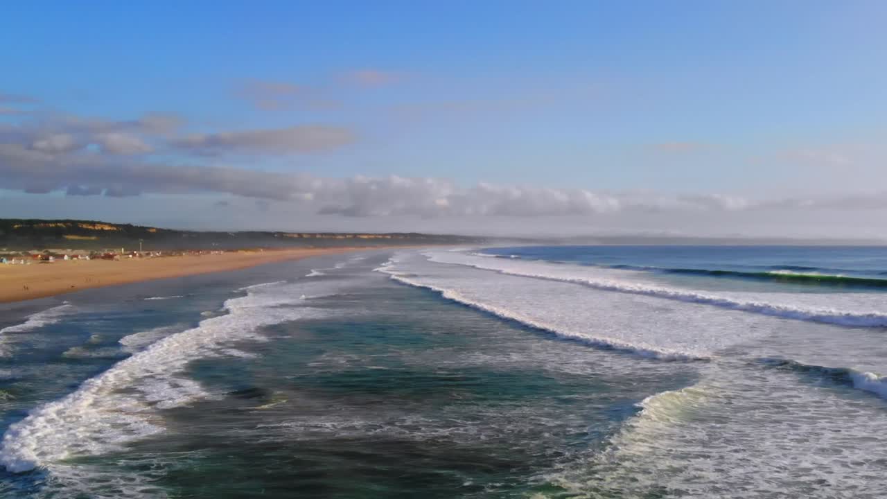 Drone shot filming waves rolling in to a big beach in Portugal