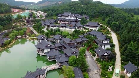 Hermosa-Vista-Aérea-En-Plataforma-Rodante-Del-Parque-Huaxiacheng-En-La-Ciudad-De-Weihai-Con-Un-Hermoso-Pueblo-Y-Un-Lago