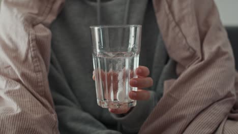 Cerca-De-Una-Mujer-Sosteniendo-Un-Vaso-Con-Una-Pastilla-Disolviéndose-En-Agua.