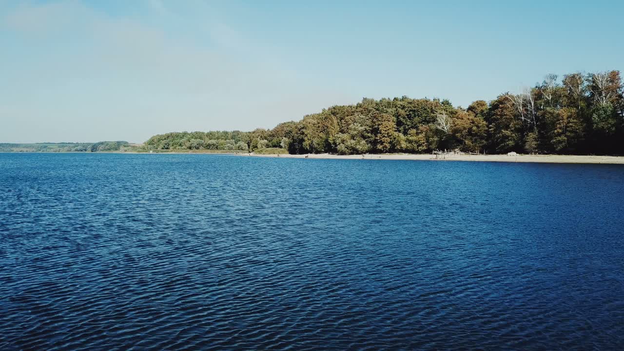 Blue and clear river with a sandy bank and forest in the summer time of the year with aerial view. Camera motion to forward. Wonderful nature.