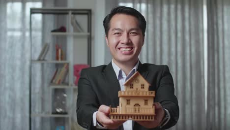 businessman holding a house model