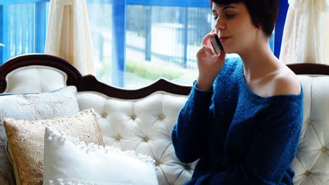 Woman-talking-on-mobile-phone-in-living-room