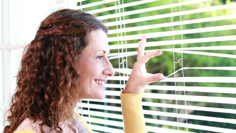 woman peering through roller blind