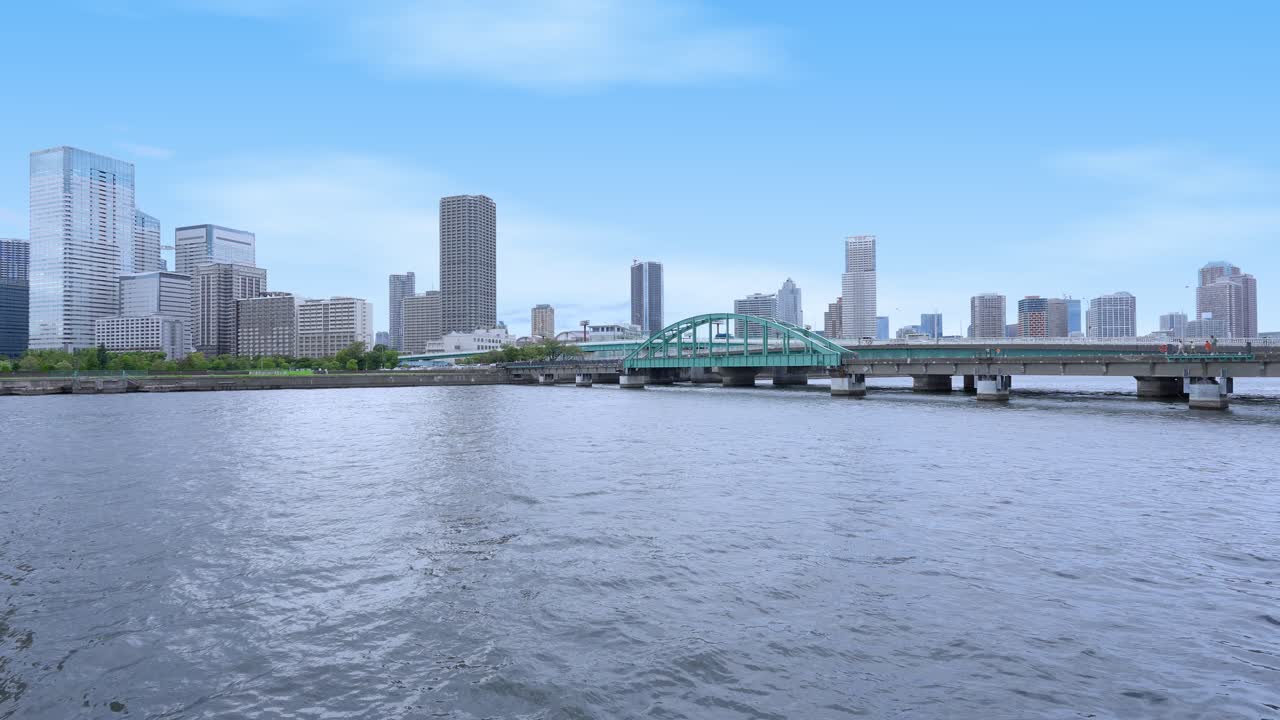A peaceful shot of the Harumi Railway Bridge and the Tokyo skyline with modern buildings under a clear sky