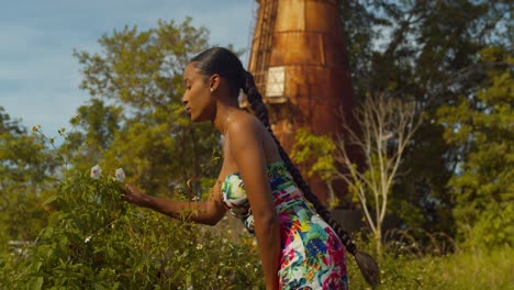 epic slow motion of a young girl walking up and smelling the roses at the base of a radar tower