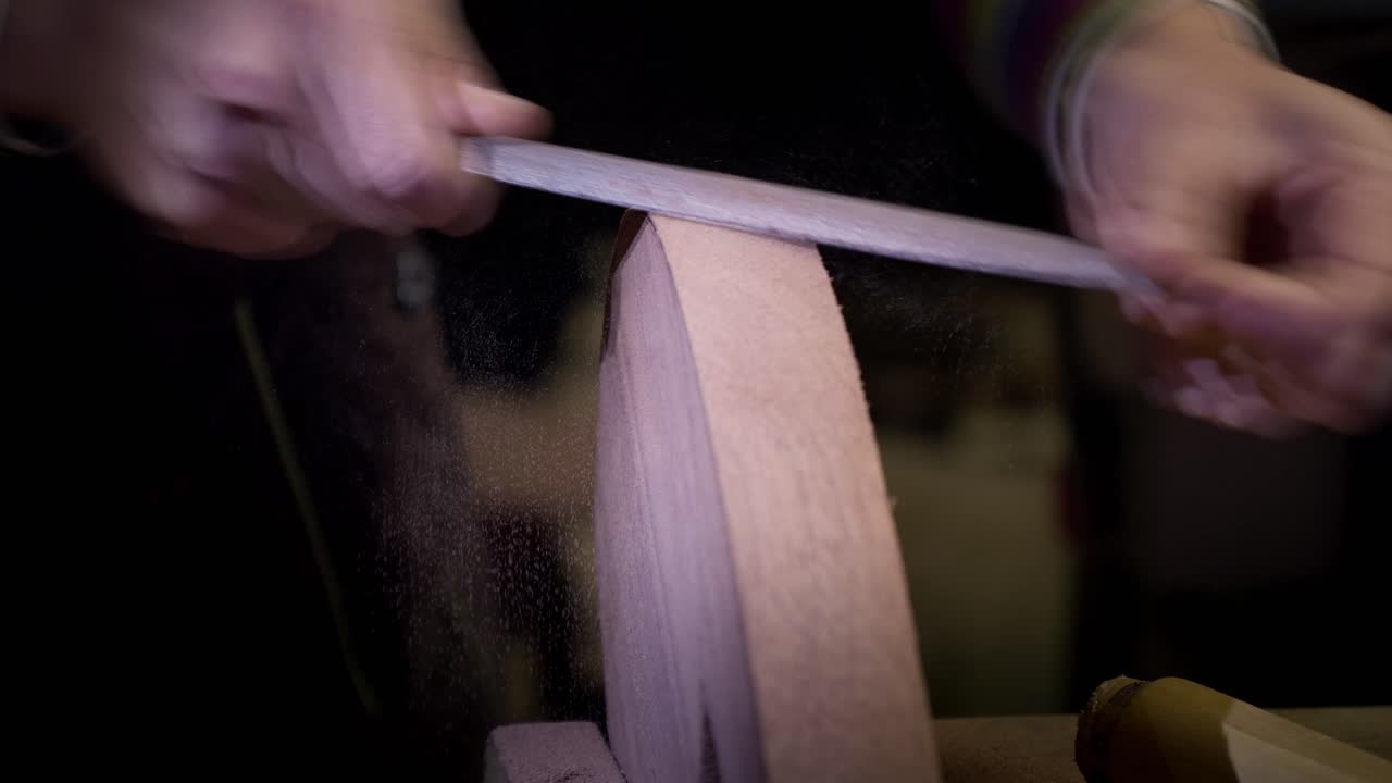 Artigiana che utilizza una lima a raspa metallica per rifinire la forma e levigare i bordi di un componente in legno curvato. Scena di laboratorio al rallentatore.